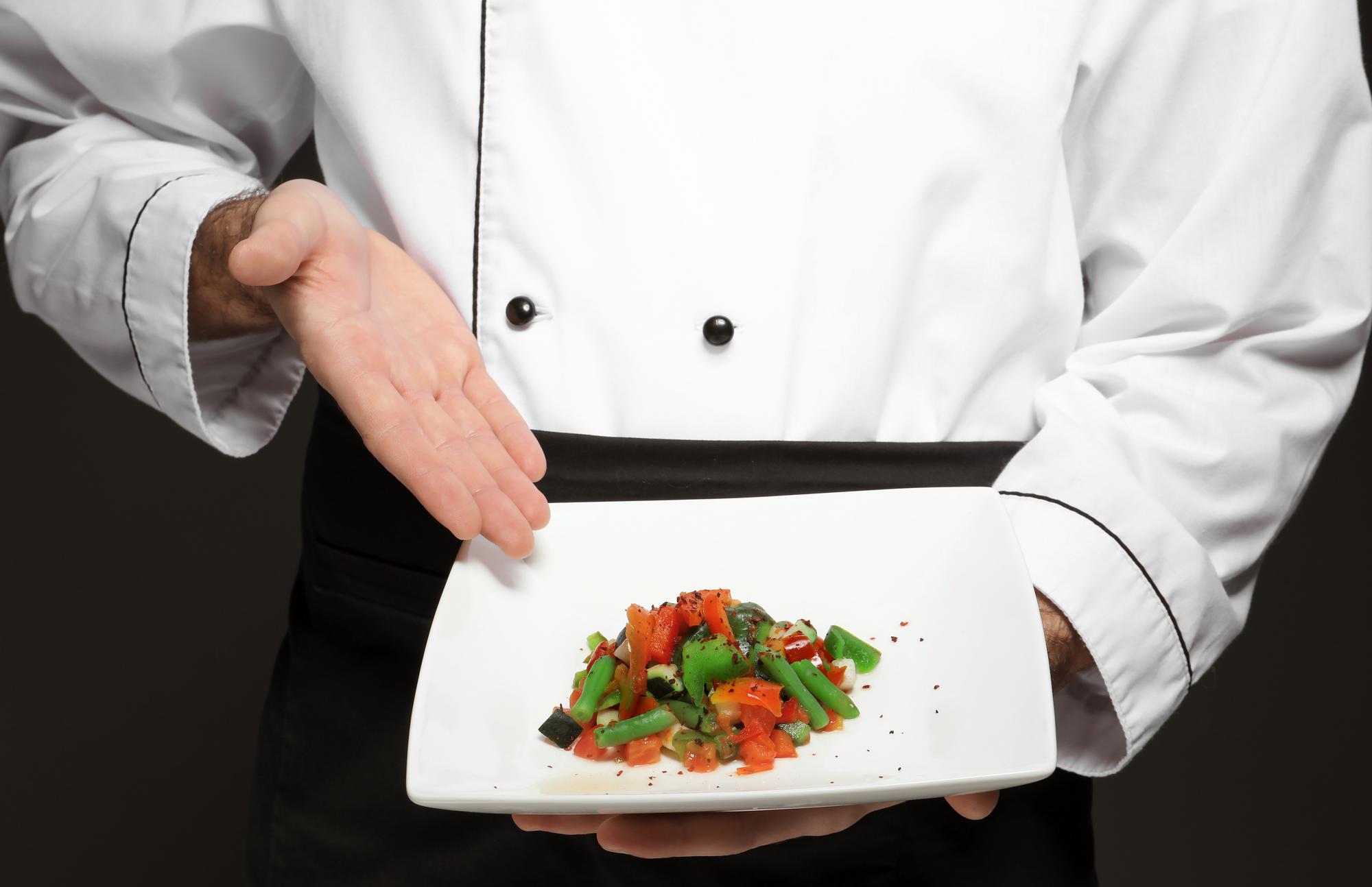 Chef plating a modern dish on a slate plate